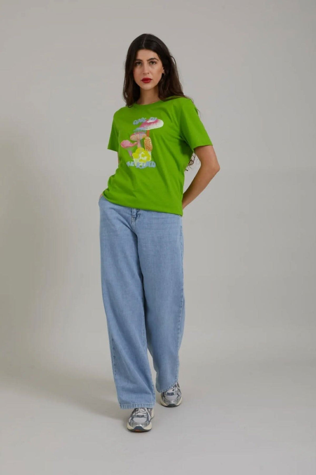 T-shirt vert avec imprimé champignon et lettrage, porté avec un jean large.
