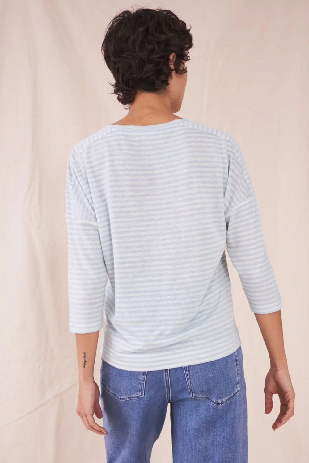 T-shirt Lennox léger et respirant, porté de dos, rayures bleu clair sur fond doux, avec manches trois-quarts.