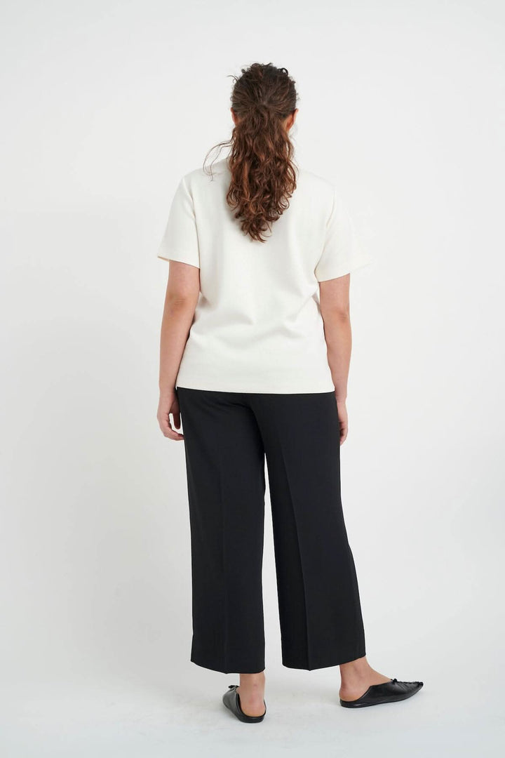 Femme vue de dos portant un t-shirt velouté Vincent avec un pantalon noir, affichant style et confort.