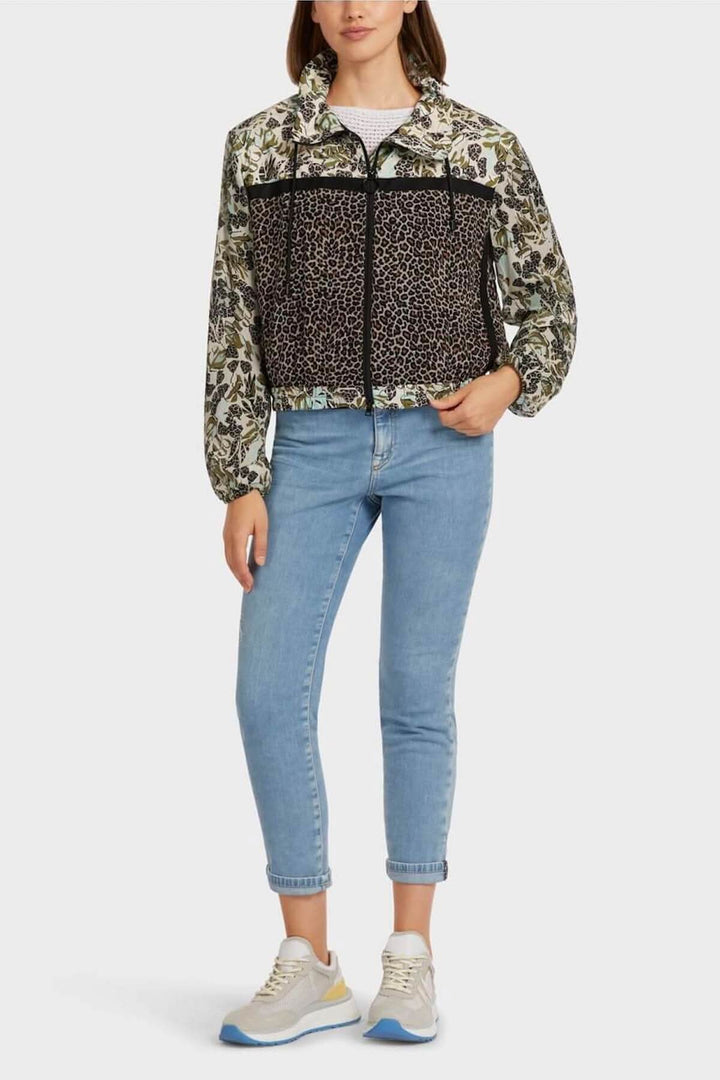 Veste féminine à motifs patchwork avec col montant et poches latérales, portée avec un jean et des baskets.